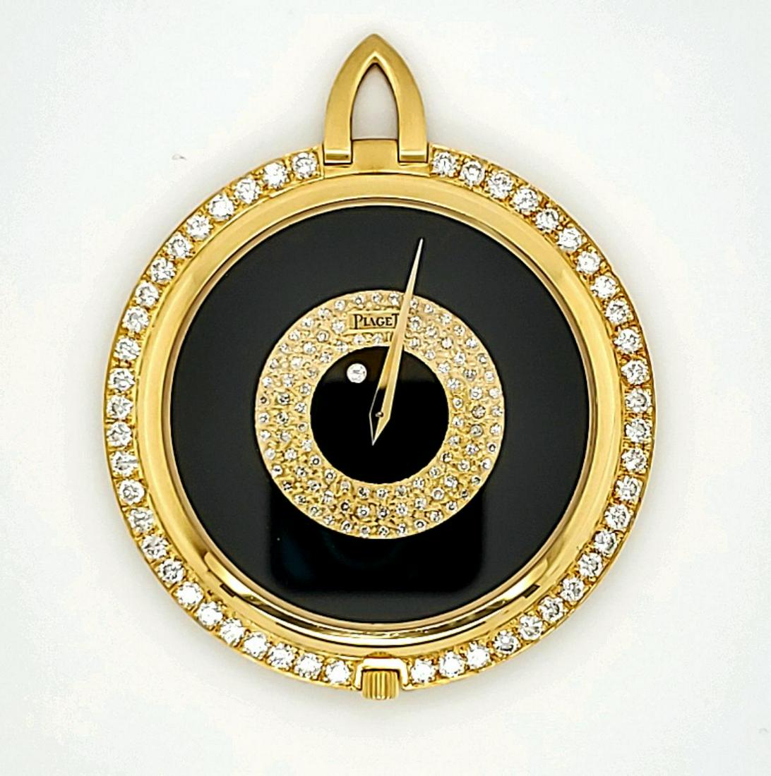 18kt yellow gold Piaget open face dress watch: Ladies 18kt yellow gold Piaget diamond and onyx open face dress watch featuring an onyx dial with pave-set diamond center, prong set round brilliant cut diamond bezel, manual wind movement and snap on