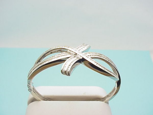 14kwg 3.5ctw diamond bangle bracelet: Lady's 14kwg diamond bangle bracelet weighing 27.4 grams. Bracelet consists of round and baguette channeled diamonds in a crossover and bypass design 3.5ctw. 21/2" inside diameter.