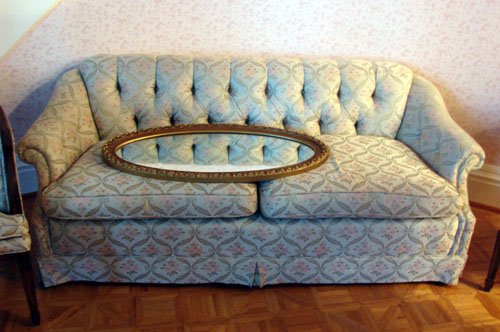 Upholstered Couch Blue Brocade: Upholstered Couch, raised on tapered legs, below upholstered seat and horseshoe shaped back support, covered in a pastel brocade.
