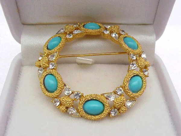 Trifari pin with CZ and turquoise: Lady's good looking pin by Trifari with round and pear shaped CZs around oval shaped turquoise mounted on a wreath of gold tone nugget.