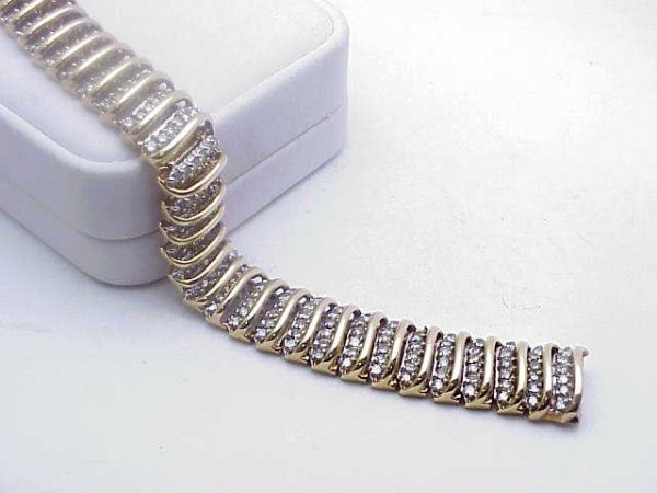 lady's 5ctw diamond bracelet 10kyg: Lady's 5ctw diamond bracelet in 10kyg weighing 44.4 grams has prong set diamonds between bars of gold 15mm wide. 7 inches in length. What a look!!