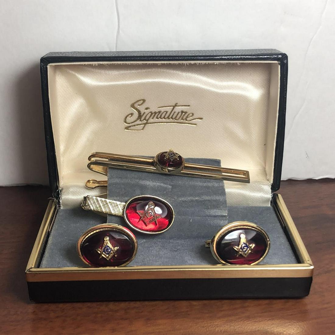 Masonic Men's Suite of Cufflinks & Tie Clip/Bar: Masonic Men's Suite of Cufflinks & Tie Clip/Bar, gold colored with Masonic Logo on red gemstone accent. Housed in a box marked "Signature". You get a pair of cufflinks, a ti clip, and a tie bar, all m
