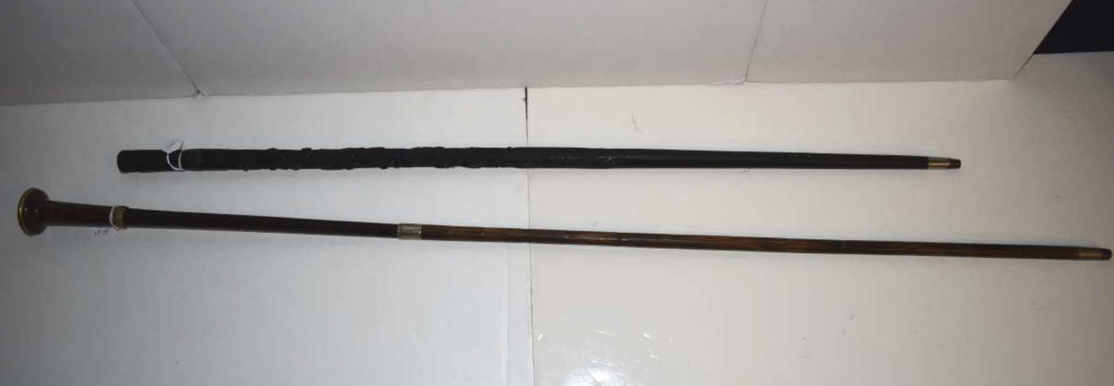 Two Canes: Two Canes. Bamboo and wood with sterling collar and metal engraved top and collar, the sterling collar was added later to aid the wood extension, 45 1/2"l. and an ebonized cane with carved clover deco