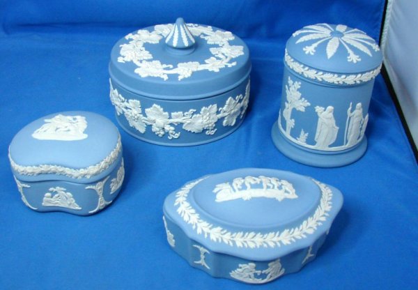 4 Covered Boxes Wedgwood Blue Jasperware: 4 Covered Boxes Wedgwood Blue Jasperware, powder box is decorated with grape vines, 5" dia., 2 1/2" high, cylindrical jar is 3 1/2" tall, two small trinket boxes are 5" and 3"; chip on rim of oval box