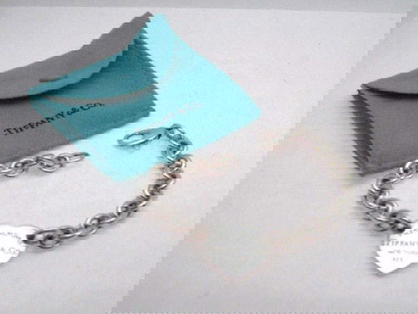 Tiffany sterling heart bracelet: Lady's Tiffany sterling heart bracelet 27.2 grams with center heart attached by rolo links and large lobster claw clasp. 7 1/2" in length. comes with box and pouch.