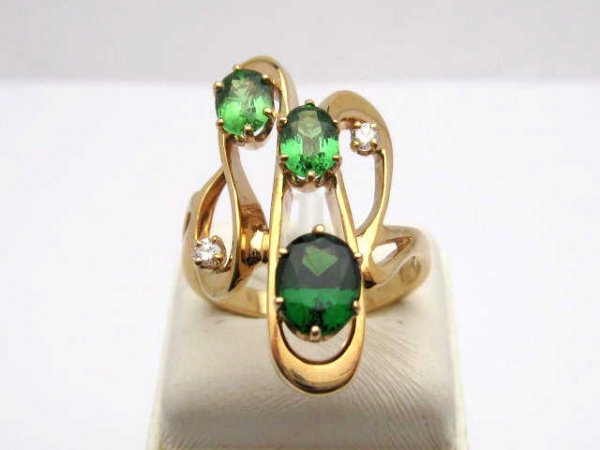 Lady's Tsavorite Garnet Ring w/diamonds: Lady's 14kyg custom ring 7.6 grams with three oval shaped tsavorite garnets approx. 4cts type1 clarity and rich vibrant green color prong set along with 2 round diamonds all set in a contemporary desi
