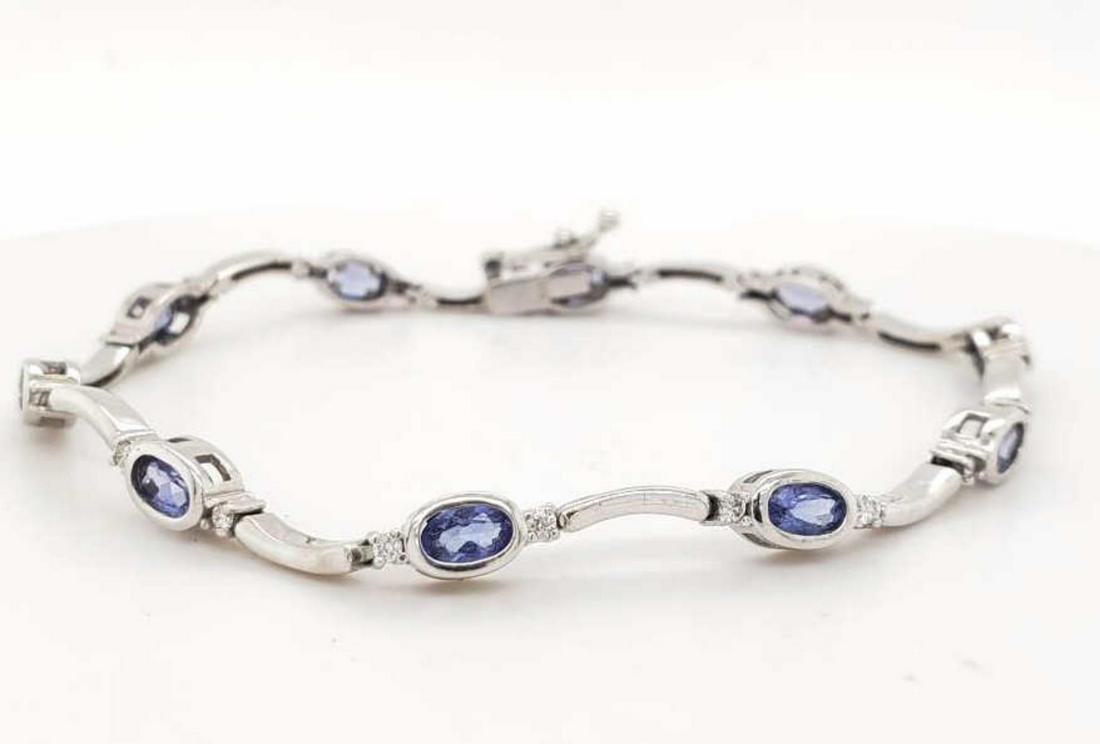14kt white gold tanzanite and diamond bracelet: Ladies 14kt white gold tanzanite and diamond bracelet featuring bezel set oval cut tanzanite weighing approx. 1.70ct.. Accented with curved bar links and prong set round brilliant cut diamonds weighin