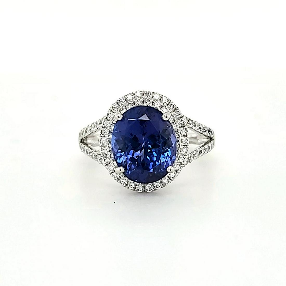 Platinum tanzanite and diamond ring: Ladies platinum tanzanite and diamond ring featuring a prong set oval cut purplish blue tanzanite weighing approx. 4.23ct.. Surrounded by a double halo and split shank design of prong set round brilli