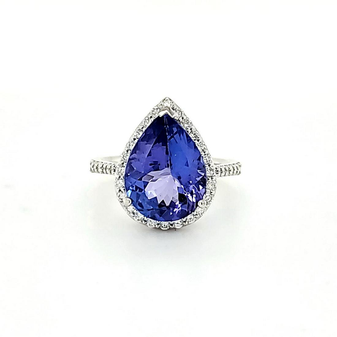 18kt white gold tanzanite and diamond ring: Ladies 18kt white gold tanzanite and diamond ring featuring a prong set pear shaped violetish blue tanzanite weighing approx. 4.66ct.. Surrounded by a halo of prong set round brilliant cut diamonds we