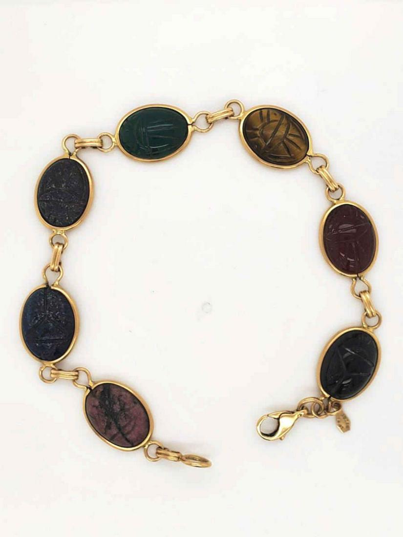 14kt yellow gold carved scarab bracelet: Ladies 14kt yellow gold carved scarab bracelet featuring bezel set carve cabochon scarabs in various color stones including onyx, carnelian, and tigers eye. Length 7 1/2. Weight 12.6 grams.