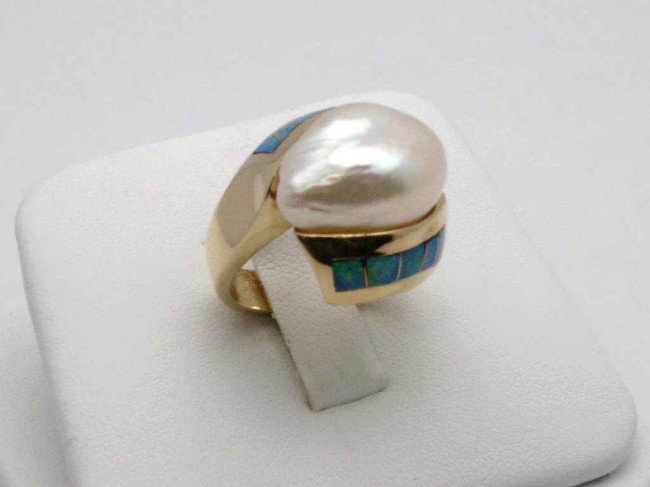 14kyg opal and pearl ring: Lady's 14kyg opal and pearl ring 13 grams with baroque shaped white pearl measuring 16x12mm channeled with flush set black opal on either side in a bypass design. Beautiful ring! Finger size 7.