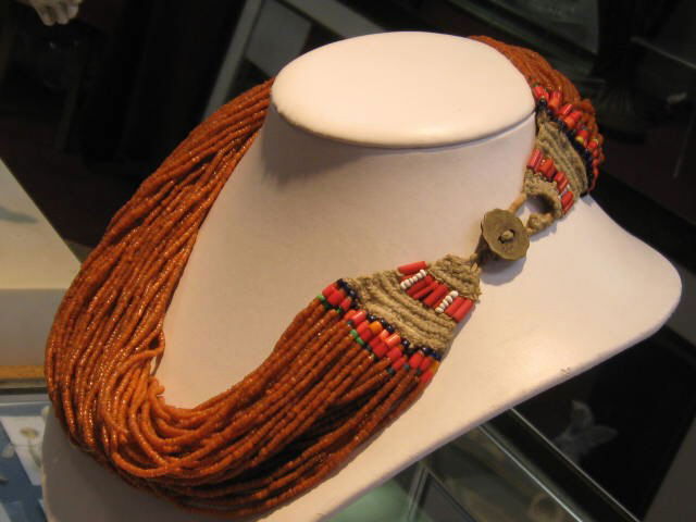 Multi strand Nagaland bead necklace: Lady's multi strand beaded necklace from Nagaland with rust colored beads and coin clasp containing multicolored beads and fabric.