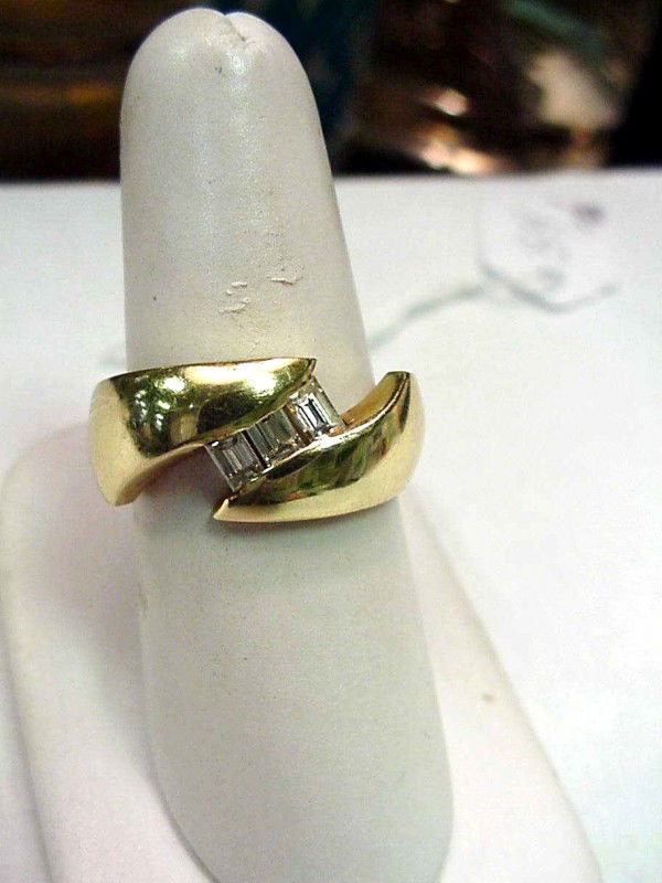 18kyg diamond wedding band .25ctw: Man's 18kyg diamond wedding band 8 grams with three rectangular diamond baguettes channel set weighing .25ctw mounted in the center of an 8mm band. Finger size 7 3/4.