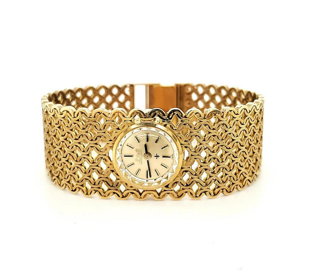 Ladies 18kt yellow gold dress watch: Ladies 18kt yellow gold Lorett dress watch featuring a wide woven circular link bracelet, manual wind movement, and acrylic crystal. Case measuring 16mm in diameter. Total width 21mm. Length 7". Gross