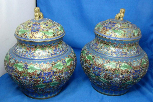 Pair of Champlevé Cloisonné Covered Ginger Jars: Pair of Champlevé Cloisonné Enameled Covered Ginger Jars with foo dog finials in shades of blue and green; 10" to top of foo's head.