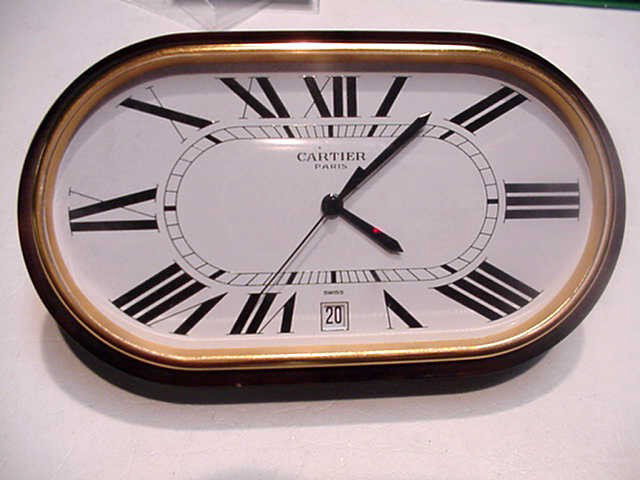 Cartier Paris desk clock: Desk clock by Cartier Paris, oval white dial roman numbers with date and Swiss quartz movement 5.5W X 2.5H.