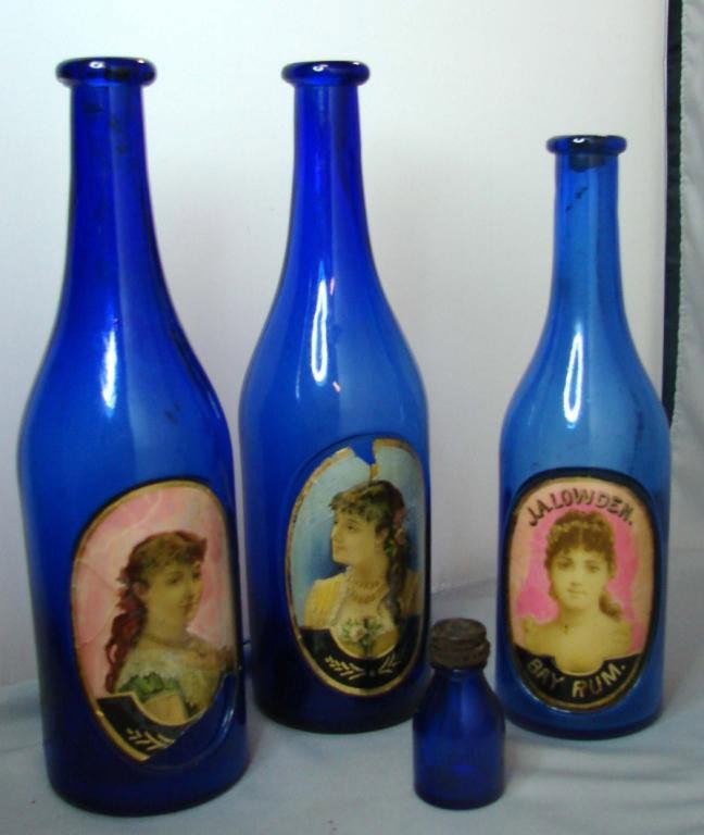 3 Vintage Cobalt Barber's Bottles + sm. bottle: 3 vintage cobalt blue barbers' bottles with glass cased pictures on the front, one is marked J.A.Lowden, Bay Rum; size 9.375" to 10.25", damage to pictures on bottles - see photo, tiny 2.5" bottle wit