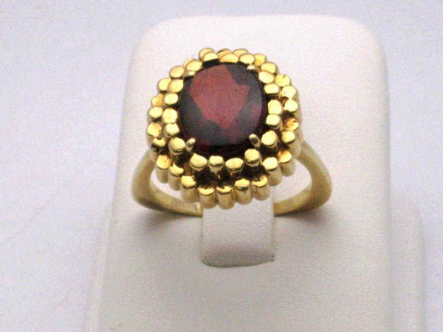 18kyg garnet ring 12.8gr: 18kyg garnet ring 12.8gr with oval shaped reversed faceted garnet weighing approx. 4ct prong set in a nugget style setting finger size 81/2.