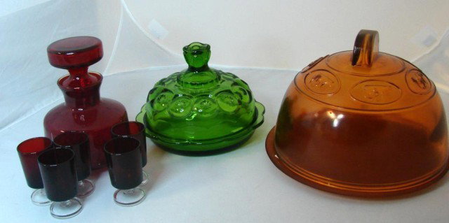 Vintage Heavy Colored Glass Cheese/Butter Dishes: Vintage heavy orange covered dish with embossed cow being milked surrounding the top, under plate is 9.75" dia., heavy green cheese or butter covered dish, small red decanter with 5 cordials.