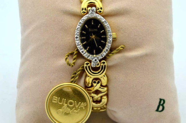 Lady's Bulova diamond watch: Lady's Bulova diamond watch with black dial and diamond bezel, quartz movement and gold plated link bracelet band.