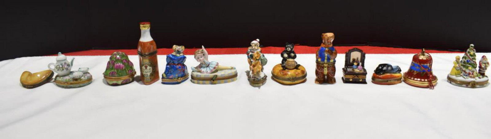 Group Of Limoges Trinket Boxes: Group Of Limoges Trinket Boxes. Total of 13 trinket boxes in the group. Sizes range from 1"-4" in height. Consists of Scotch Whiskey Bottle. Ornament Bell. Fortune Cookie. Santa Claus, Mrs Claus, & Ch