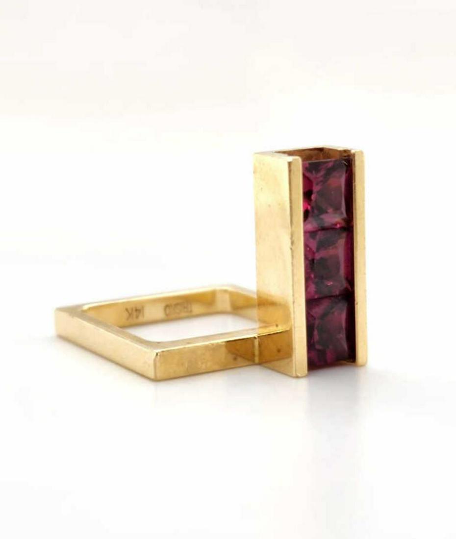 14kt yellow gold garnet fashion ring: Ladies 14kt yellow gold garnet fashion ring featuring channel set princess cut garnets 2.70ct. and mounted on a geometric square band. Band width 2mm. Finger size approx. 5.5. Weight 8.8 grams. (25)