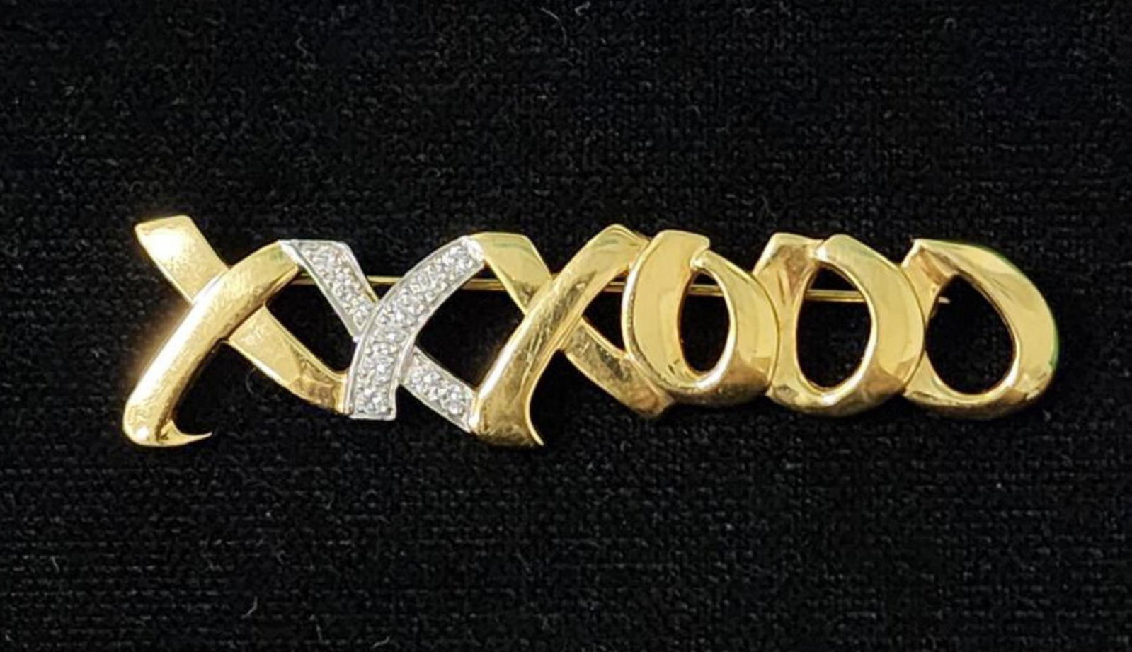 18kt yellow gold Tiffany & Co diamond "XO" pin: Ladies 18kt yellow gold Tiffany & Co. Paloma Picasso diamond "XO" pin featuring a high polish signature 'XO" pattern accented with prong set round brilliant cut diamonds weighing approx. 0.22ct., Clar