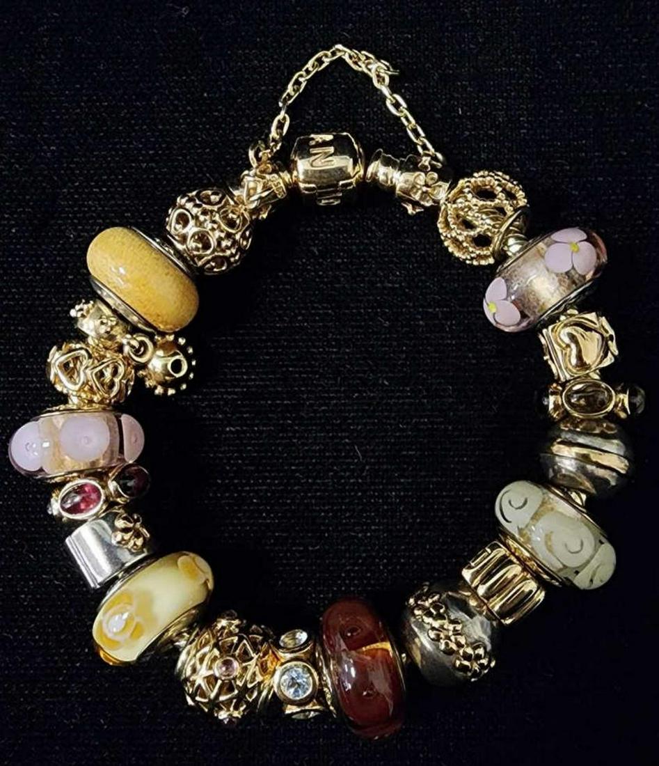 14kt yellow gold Pandora charm bracelet: Ladies 14kt yellow gold Pandora charm bracelet featuring mainly 14kt yellow gold charms including Murano glass, open hallow design beads, floral designs and colored stones. 6 beads contain sterling si