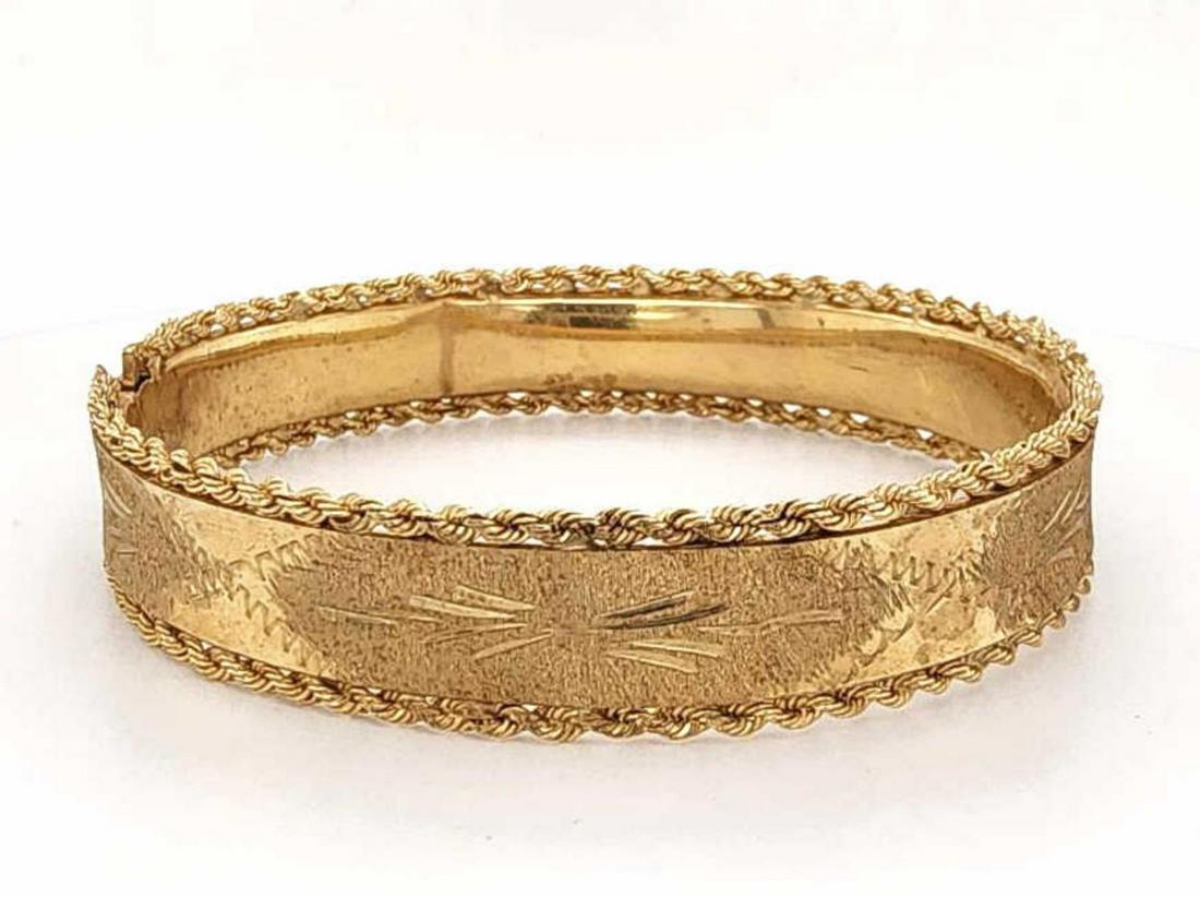 14kt yellow gold bangle bracelet: Ladies 14kt yellow gold bangle bracelet featuring an etched floral design, satin finished and twisted rope edge. Diameter 2 1/4". Width 12mm. Weight 16.7 grams. There are 2 visible dents in the piece.