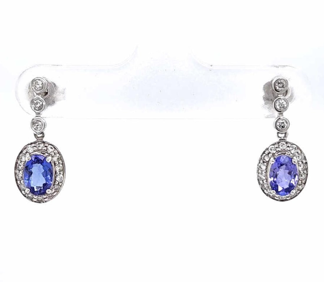 14kt white gold tanzanite and diamond earrings: Ladies 14kt white gold tanzanite and diamond earrings featuring prong set oval cut tanzanites weighing approx. 0.80ct. Surrounded by a halo of prong set round diamonds weighing approx. 0.20ct., Clarit