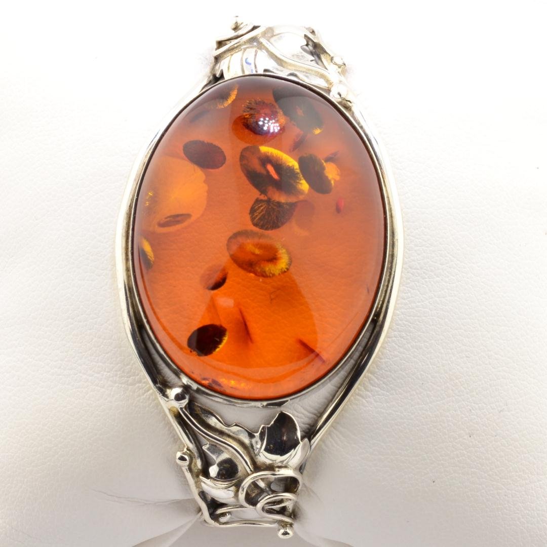 Ladies Silver Amber Bracelet: Ladies Silver Amber Bracelet. 26 x 35mm oval Amber bezel set on top of floral bangle. Opens as cuff bracelet with safety snap. Length 2 1/2" wide. 26.2gr