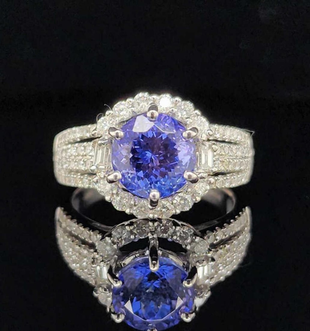 18kt white gold tanzanite and diamond ring: Ladies 18kt white gold tanzanite and diamond ring featuring a prong set round medium dark, slightly grayish, violetish blue tanzanite weighing approx. 2.57ct. Accented with a halo and shoulders of pro