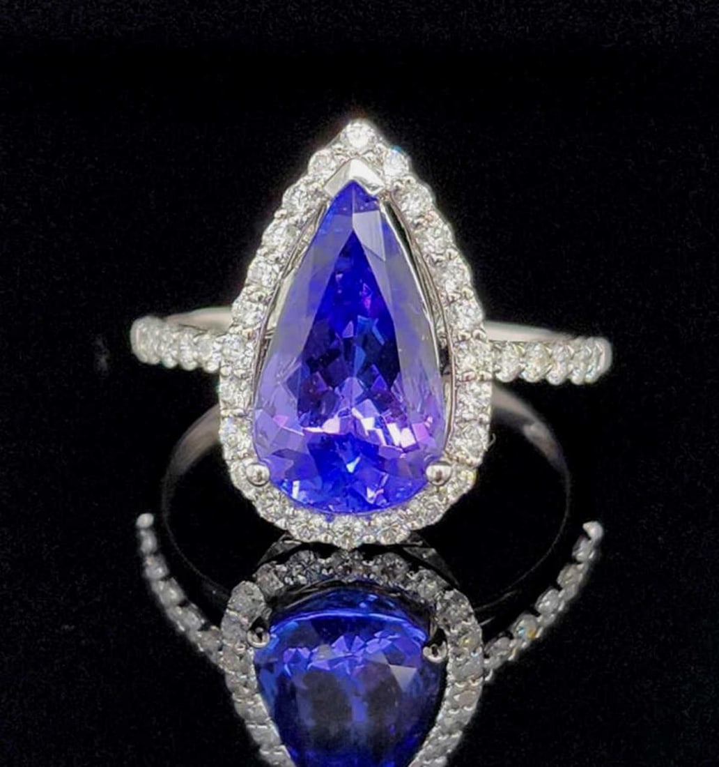 14kt white gold tanzanite and diamond ring: Ladies 14kt white gold tanzanite and diamond ring featuring a prong set pear shaped bluish violet tanzanite weighing approx. 2.95ct.. Surrounded by a halo of prong set round brilliant cut diamonds wei