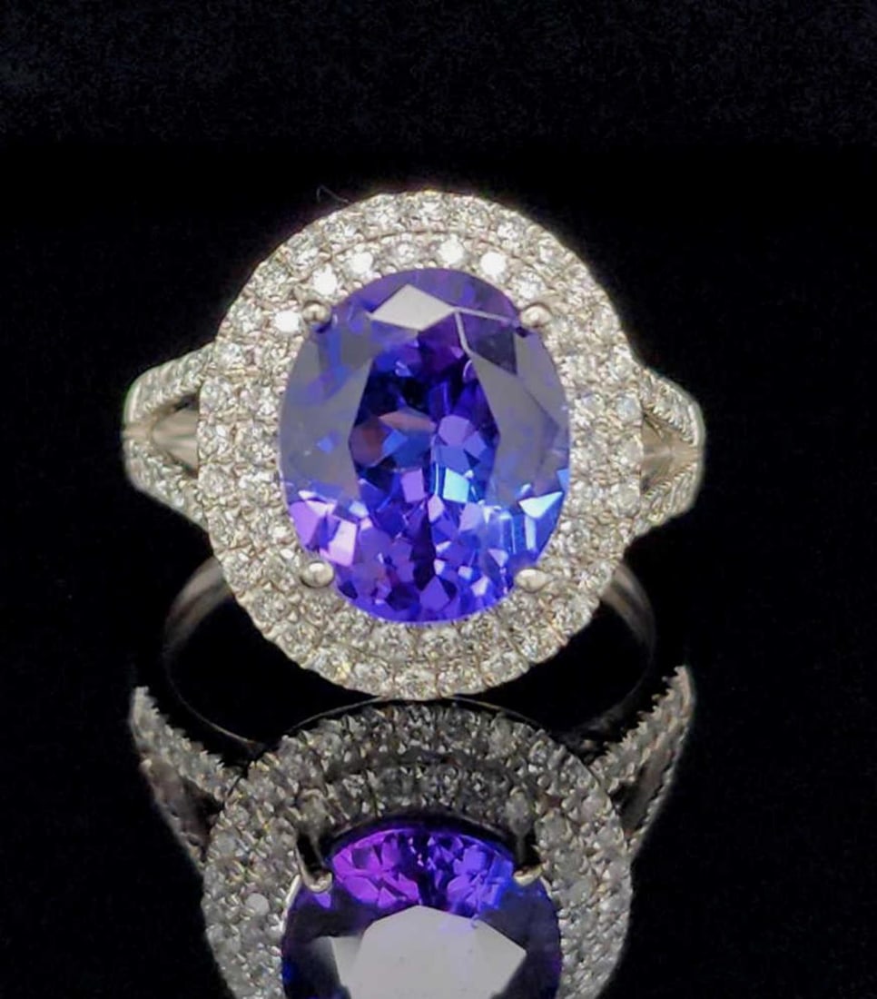 Platinum tanzanite and diamond ring: Ladies platinum tanzanite and diamond ring featuring a prong set oval cut violetish blue tanzanite weighing approx. 3.52ct. Surrounded by a double halo of prong set round brilliant cut diamonds weighi