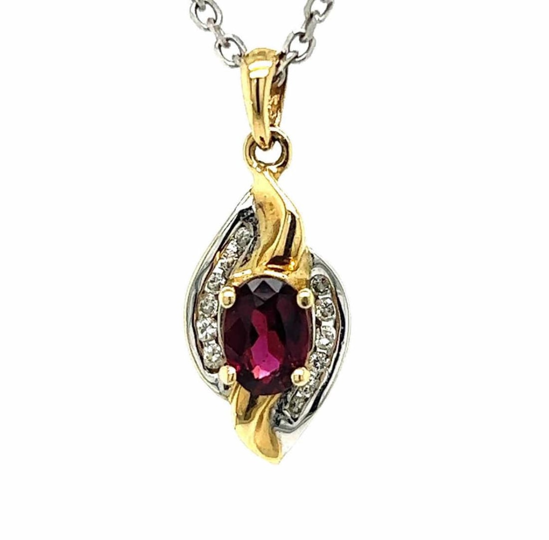 14kt two tone garnet and diamond pendant: Ladies 14kt two tone garnet and diamond pendant featuring a prong set oval cut garnet weighing approx. 0.63ct.. Accented with a flowing frame of channel set round diamonds weighing approx. 0.06ct. Han