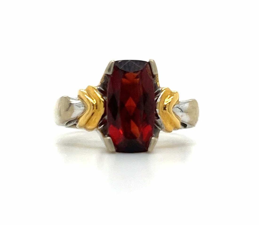 14kt two tone garnet fashion ring: Ladies 14kt two tone garnet fashion ring featuring a prong set rectangular garnet weighing approx. 2.82ct.. Accented with a ridged design. Finger size 5.5. Weight 7.8 grams.