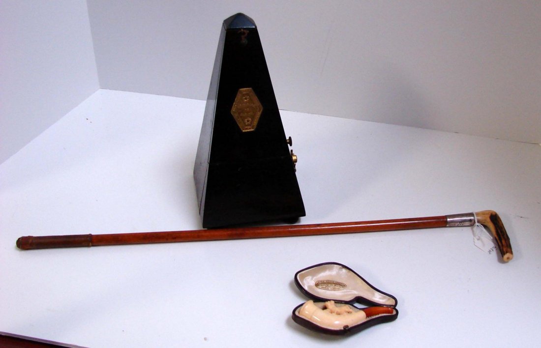 Antique Riding Crop, Carved Ivory Pipe, Metronome: Antique Riding Crop. Engraved A. M.G. Stamped A A and the Lion 20" l, miniature ivory pipe with carved dog in case marked Berlin Dresden 3.5" l, and a Maelzel Metronome.
