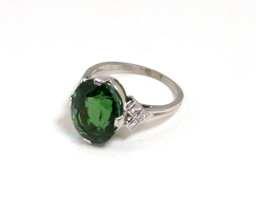 Platinum Green Tourmaline Ring Tiffany & Co: Lady's platinum tourmaline & diamond ring by Tiffany & Co with oval shaped green tourmaline weighing 6.35ct, prong set good color and clarity, along with three square cut diamonds on each shoulder .24