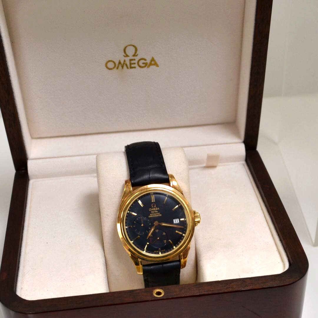 18kyg Omega Co-Axial Chrono Watch: Man's 18kyg Omega Deville Co-Axial chrono watch with black face and gold hands, date, 3 dial face, Swiss auto movement with power reserve, original black leather band, box and papers.