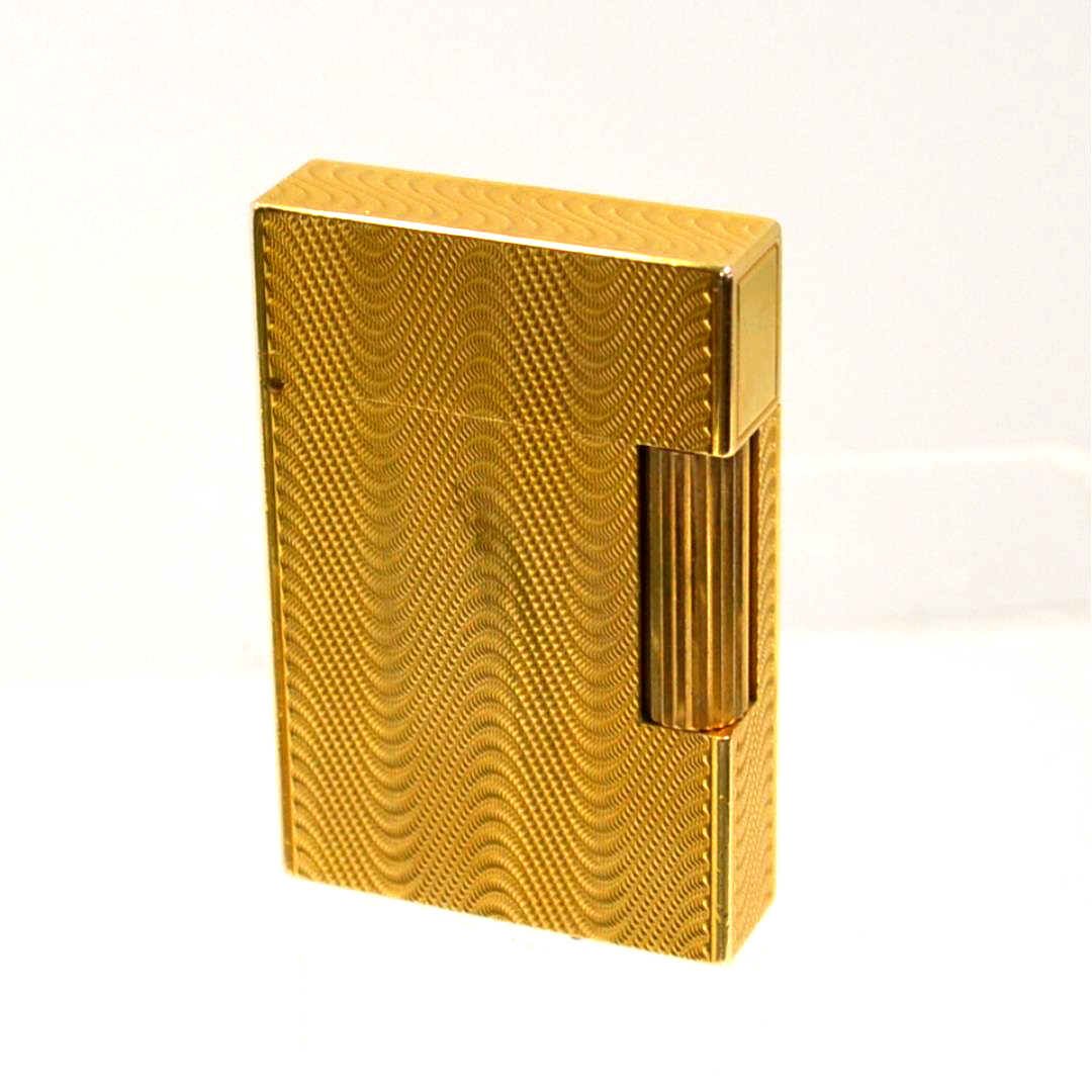 Vintage S.J. DuPont Lighter: Vintage S.J. DuPont lighter with wave textured design, gold electroplate finish, roller lighting mechanism, 11/4" high and made in France.