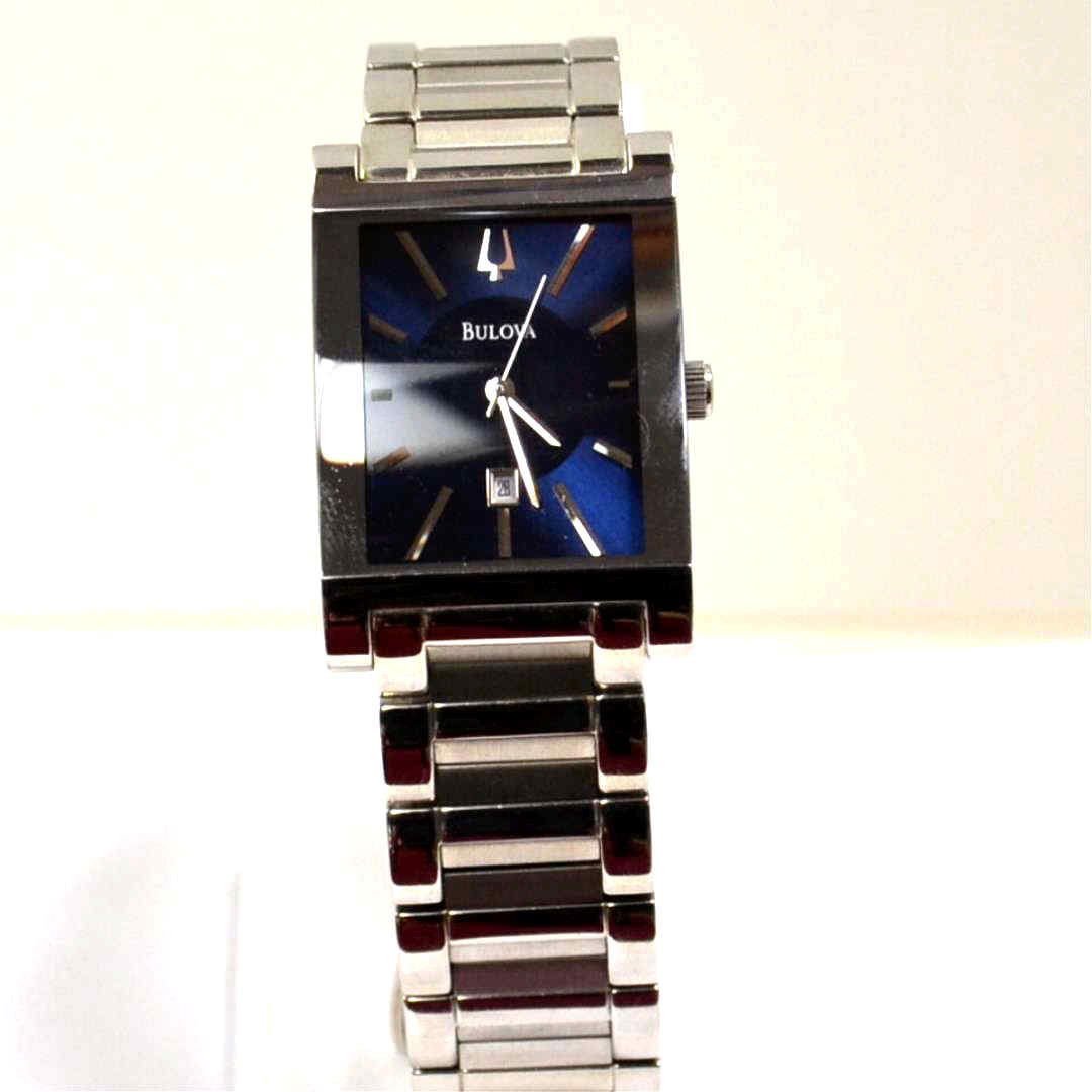 Man's Bulova Dress Watch Blue Dial: Man's stainless Bulova dress watch with rectangular case 28mm in width with blue stick dial with date, water resistant, quartz movement and alternating polish and satin band. Needs battery.