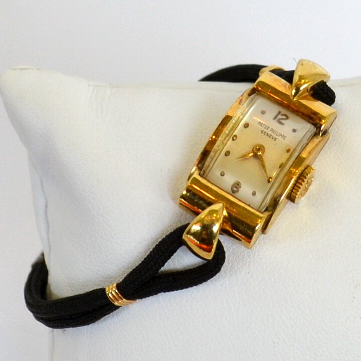 Lady's 18kyg Patek Philippe Watch: Lady's vintage 18kyg Patek Philippe watch with rectangular face and gold hands, 15mm case with crown, 18 jewel movement, black nylon band and good running condition. Case #627370 17.3gm