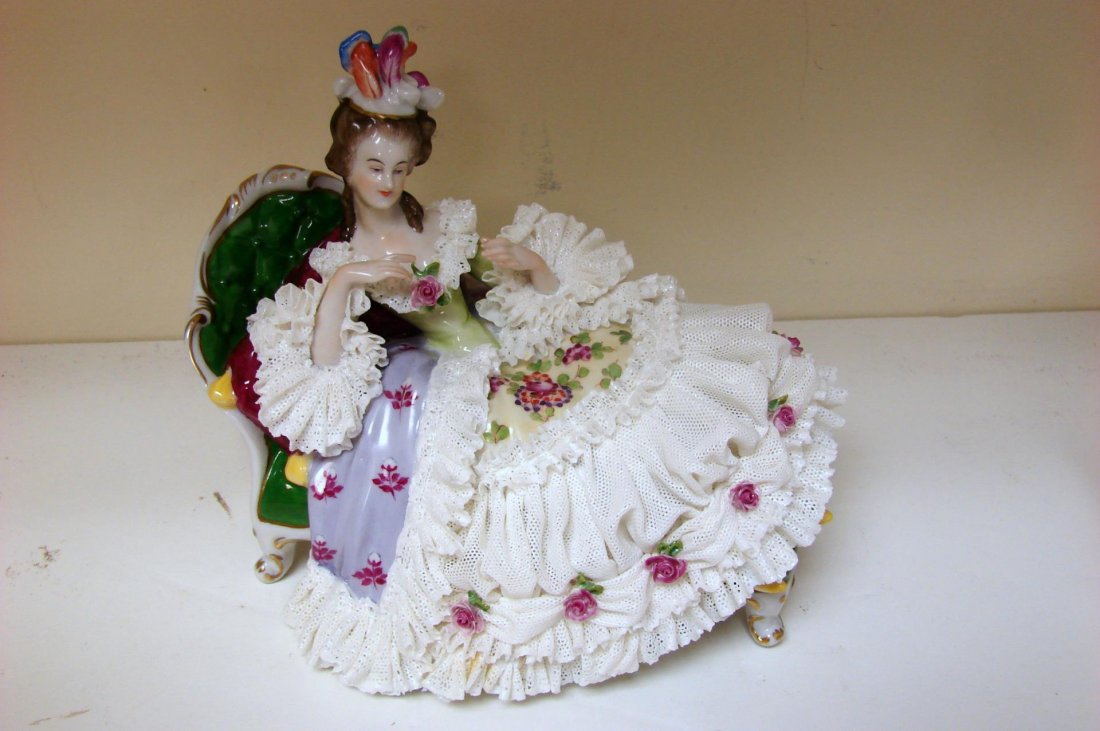 Antique Lace Trimmed Dresden Figurine: Antique Lace Trimmed Dresden Figurine of a Woman on a Couch in a white gown trimmed in red roses, approx. 7.5" long x 5" high; some small loss to lace on bottom of gown.