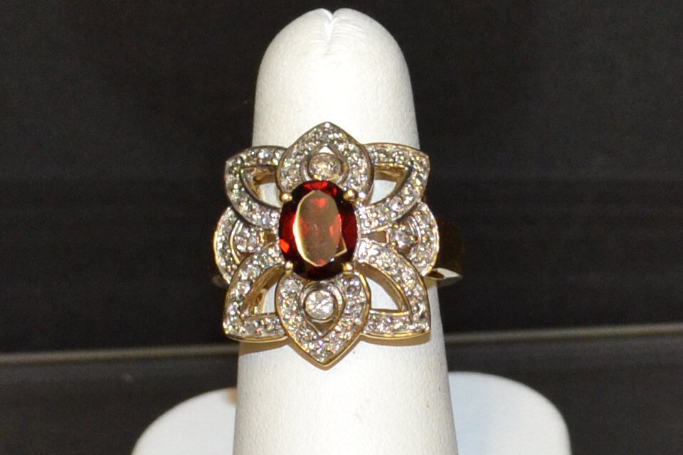 14kyg Garnet & Diamond Ring: 14kyg garnet and diamond ring with one oval shaped garnet weighing approx. 2ct, surrounded by bezeled and prong set diamonds, weighing .85ctw, finger size 6 1/4. 9.8gm
