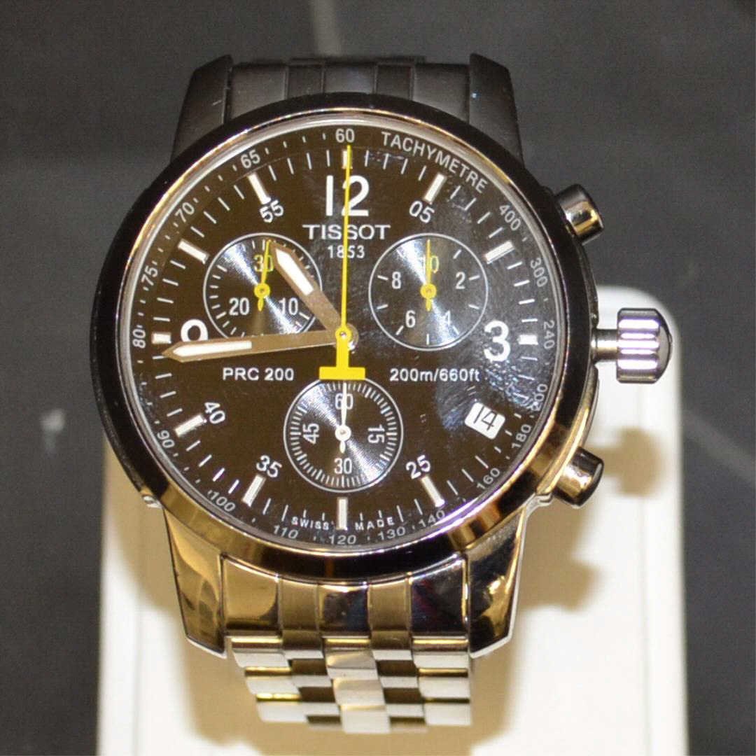 Stainless Tissot PRC200 Chronograph Watch: Man's stainless Tissot PRC200 chronograph watch with black dial and 3 sub dials, illuminated hands, sapphire crystal, water resistant and Swiss movement. Some scratches on the buckle.