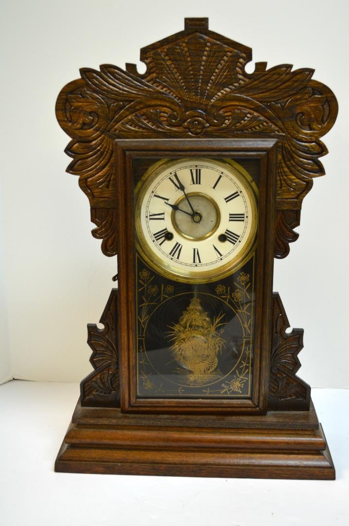 New Haven Gingerbread Mantel Clock: New Haven Gingerbread Mantel Clock. Eight day, time/strike clock with brass works, paper over tin dial, reverse decorated door and pressed oak case, includes key and pendulum, 22 1/4"h.