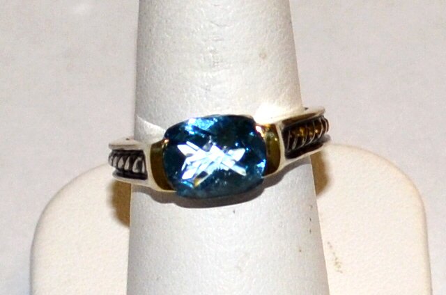 David Yurman Sterling & 18kyg Blue Topaz Ring: David Yurman sterling and 18k ring containing one oval shaped blue topaz, measuring 10x8mm, cable design on shoulders, finger size 7. 6.1gm Small chip on stone.
