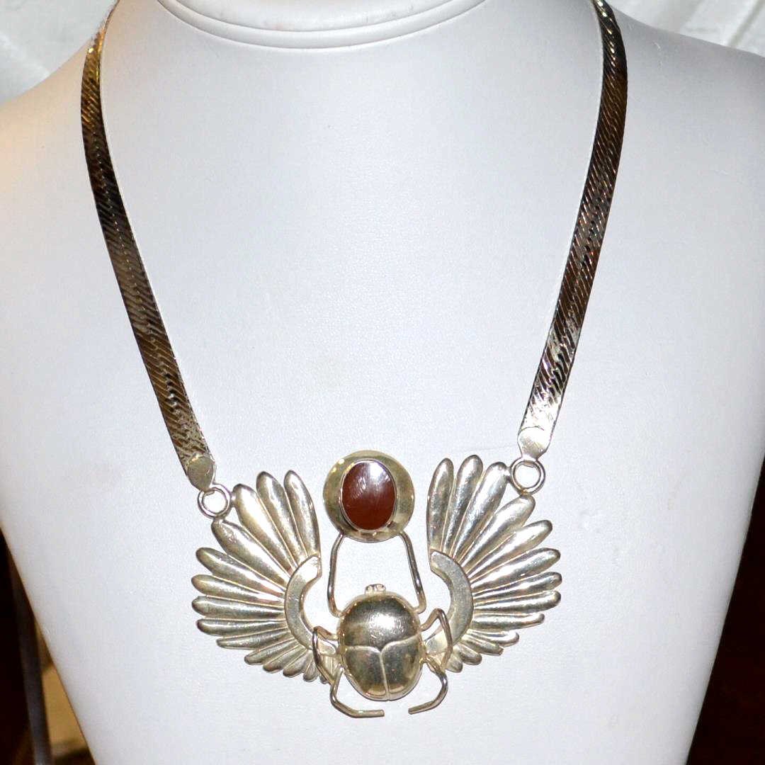 Sterling Scarab Necklace: Sterling scarab beetle necklace with feathers. 3" in length and oval shaped carnelian, 7mm herringbone chain, 20" in length.