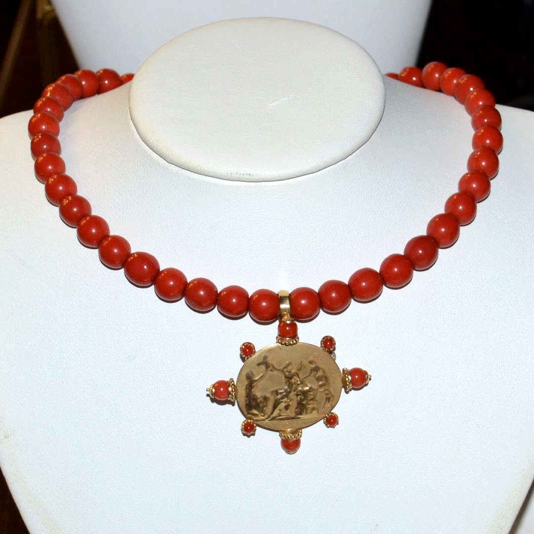 19" Red Coral Necklace With 14k Intaglio: Red coral necklace, 9" beads with 14kyg intaglio from Italy, framed in red coral beads, measuring 2x1 3/4". Can be detached and used as a pin. Necklace is spring designed to accommodate up to 19". 10g