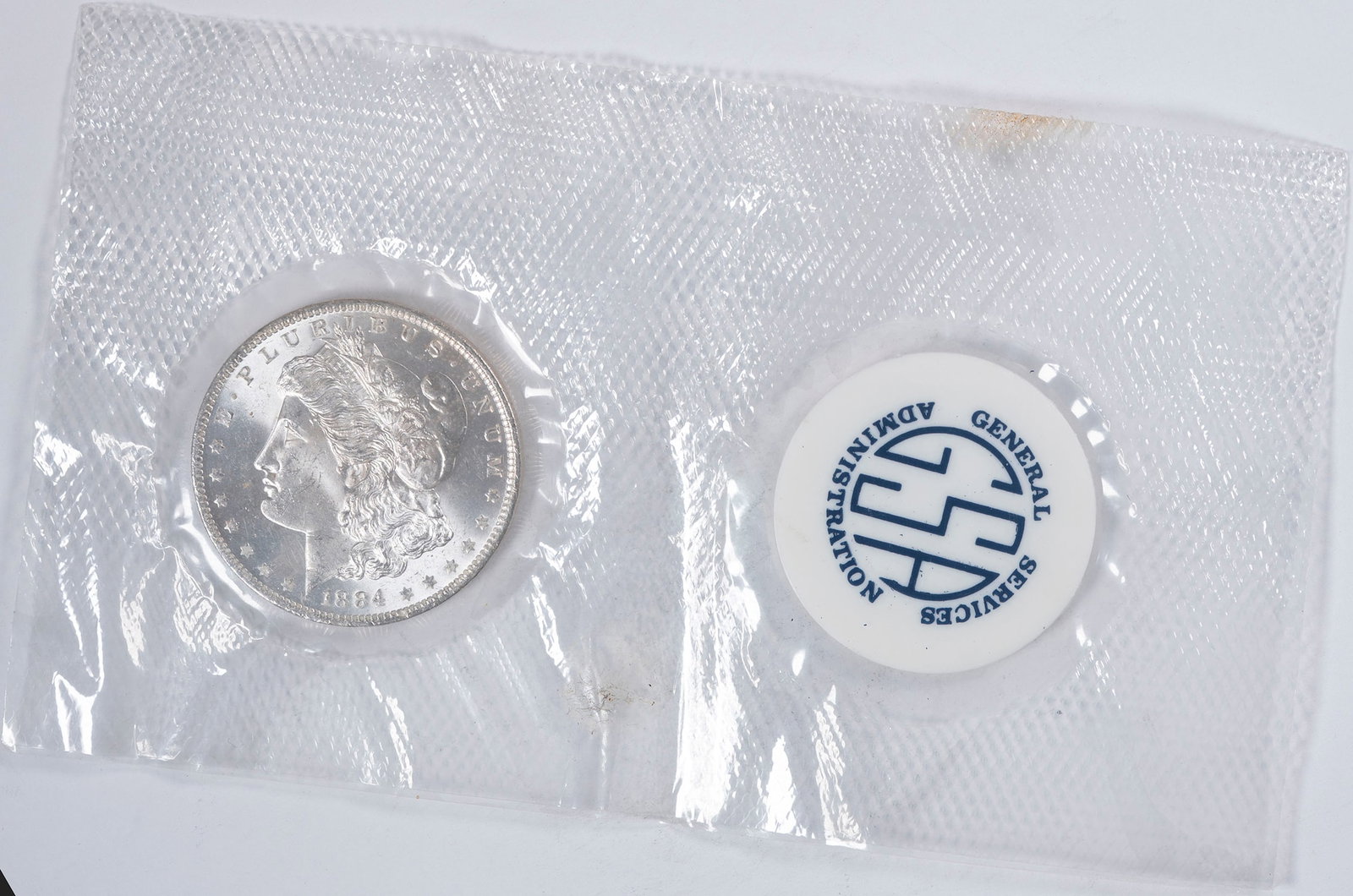 Choice MS-64 1884-O Pliofilm GSA Morgan Dollar: Bright and lustrous with sharp devices and a near-Gem overall appearance. In a pliofilm package, and much scarcer than the same coin in a typical GSA holder.